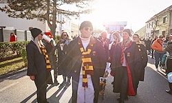 Eine Gruppe von Menschen in Harry Potter-Kostümen, einschließlich Schals und Roben, geht während einer Veranstaltung eine Straße entlang.