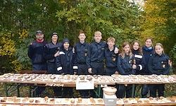 Eine Gruppe von Menschen in passenden Uniformen posiert für ein Foto vor einem Tisch, der mit verschiedenen Steinen und Felsen bedeckt ist.