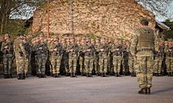 Eine Gruppe von Soldaten in Tarnuniformen steht in einer Reihe, wobei ein Soldat vor ihnen steht und sie ansieht.