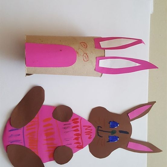 Zwei handgefertigte Kaninchen-Basteleien, eine aus einem Pappkarton mit rosa Ohren und die andere ein flaches braunes Kaninchen mit rosa Ohren und blauen Augen.