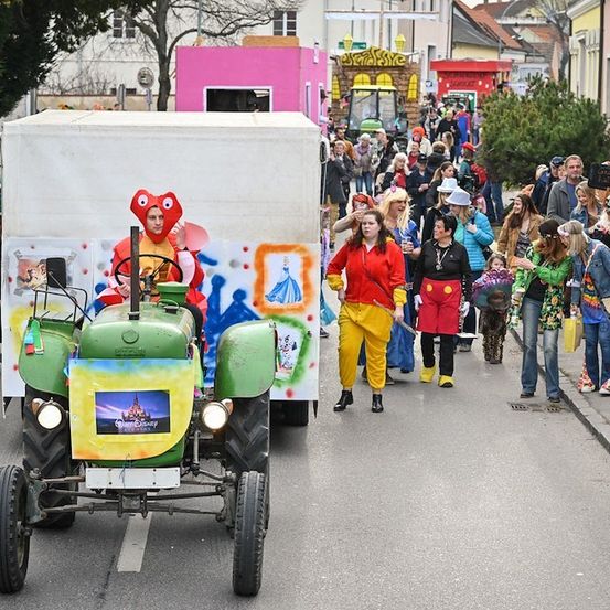 Ein Umzug mit einem Traktor, der als Micky Maus dekoriert ist, mit Leuten in Kostümen, die auf der Straße gehen.