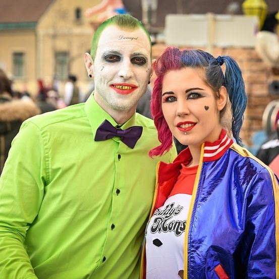 Ein Mann, der als Joker verkleidet ist, und eine Frau, die als Harley Quinn verkleidet ist, stehen bei einer Kostümveranstaltung zusammen.