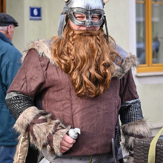 Eine Person verkleidet als Wikinger mit langem Bart, gehörntem Helm und Schwert.