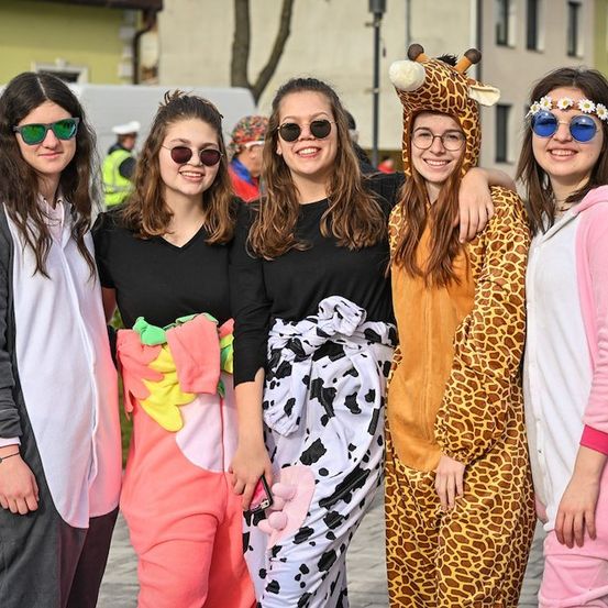 Fünf Frauen in Tier-Pyjamas posieren an einem sonnigen Tag für ein Foto, eine trägt einen Giraffenhut.