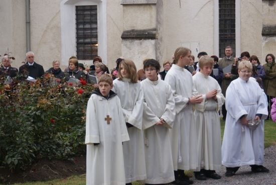 Eine Gruppe junger Menschen in weißen Gewändern steht vor einer Kirche, möglicherweise während einer religiösen Zeremonie.