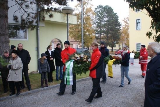 Eine Gruppe von Menschen in Winterkleidung trägt Kränze vor einem Gebäude.