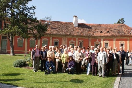 Eine Gruppe von Menschen posiert für ein Foto vor einem alten Gebäude mit rotem Dach und weißer Einfassung.