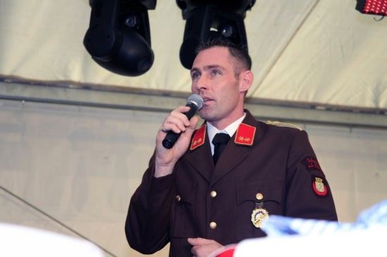Ein Mann in Uniform spricht in ein Mikrofon bei einer Veranstaltung.