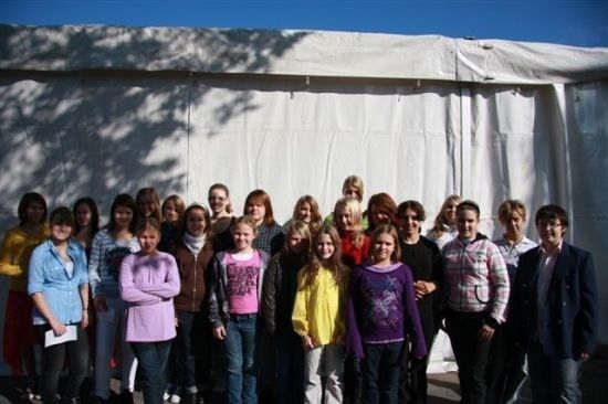 Eine Gruppe junger Menschen, sowohl Mädchen als auch Jungen, steht zusammen vor einem weißen Zelt. Sie alle lächeln für ein Foto.