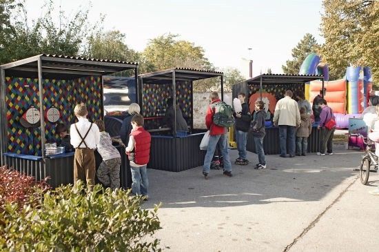 Eine Gruppe von Menschen steht in einer Schlange an einem Schießstand mit farbenfrohen Zielen an der Wand.