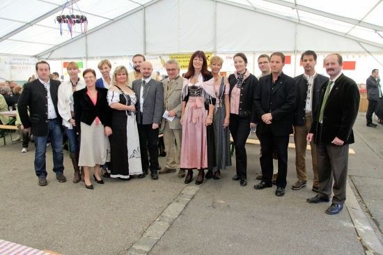 Eine Gruppe von Menschen, möglicherweise eine Familie, steht in einem Zelt mit weißem Dach und lächelt für ein Foto.