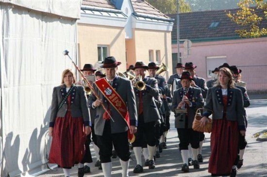 Eine Gruppe von Menschen in traditionellen Kostümen, die mit Musikinstrumenten bei einer Parade marschiert.