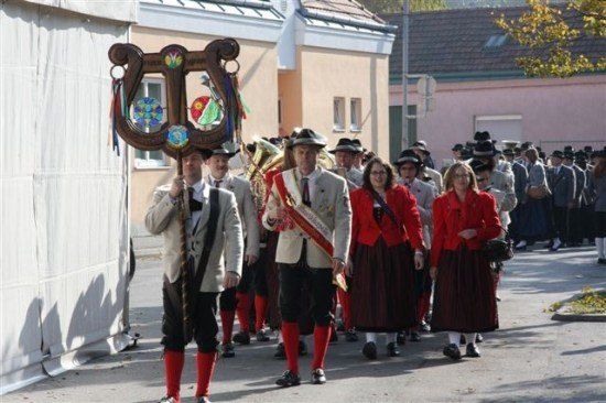 Eine Gruppe von Menschen in traditioneller Kleidung zieht mit Musikinstrumenten bei einer Parade.