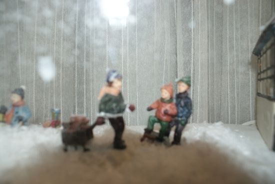 Eine Miniaturszene von Kindern, die im Schnee spielen, wobei eines einen Schlitten hält.