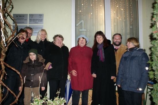 Eine Gruppe von Menschen posiert für ein Foto vor einem Gebäude mit einem Schild, das SCHGV steht.