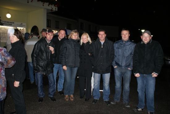 Eine Gruppe von Menschen in Winterkleidung steht nachts draußen.