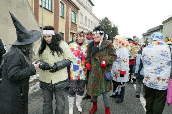 Eine Gruppe von Menschen in bunten Kostümen und Hüten steht auf einer Straße, möglicherweise an einem Umzug teilnehmend.