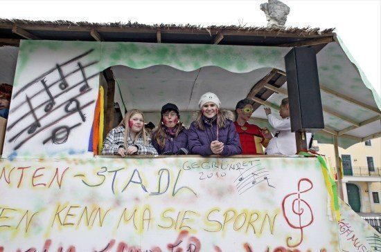 Vier Frauen in einem geschmückten Wagen mit Noten und Graffiti an der Seite, lächeln und posieren für die Kamera.