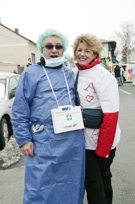 Ein Mann, der als Arzt verkleidet ist, und eine Frau, die als Krankenschwester verkleidet ist, stehen lächelnd für ein Foto auf einer Straße.