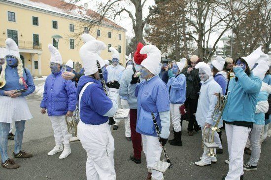 Eine Gruppe von Menschen in blauen und weißen Kostümen, einschließlich Kochmützen und Gesichtsbemalung, steht in einer Reihe, möglicherweise bei einer Parade auftretend.