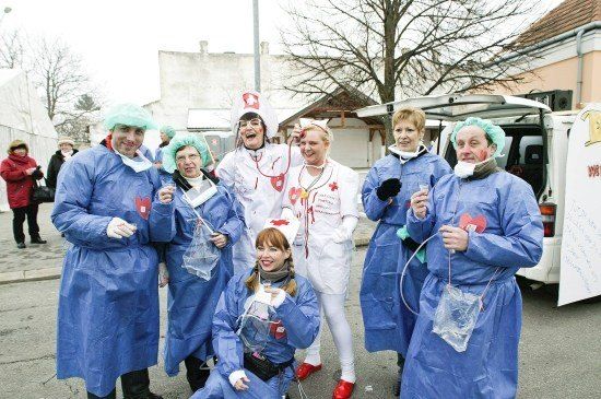 Eine Gruppe von Menschen in medizinischen Uniformen und Masken, die lächelnd für ein Foto auf einer Straße posieren.