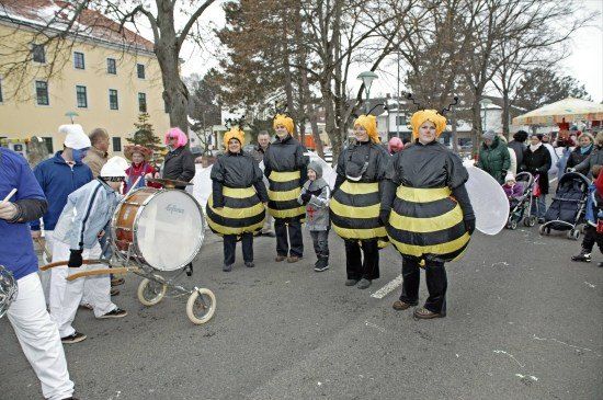 Eine Gruppe von Menschen, die als Bienen verkleidet sind, mit einer Person, die eine Trommel spielt, marschiert in einem Umzug.