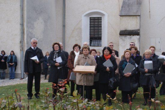 Eine Gruppe von Menschen in Winterkleidung steht vor einem Gebäude, einige halten Papiere und andere Bücher.