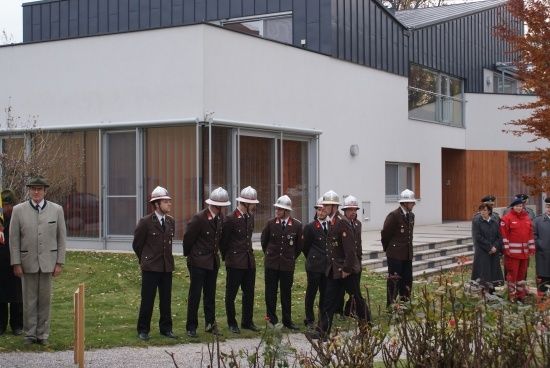 Eine Gruppe von Feuerwehrleuten in Uniform steht vor einem modernen Gebäude mit Glasfenstern.