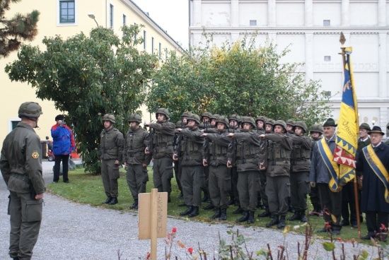 Eine Gruppe von Soldaten in Uniform steht in Formation vor einem Gebäude mit einer Fahne.
