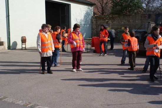 Eine Gruppe von Menschen in orangefarbenen Westen und mit Stöcken stehen auf einem Parkplatz.