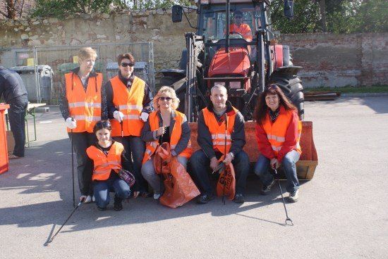 Eine Gruppe von Menschen in orangenen Westen posiert für ein Foto mit einem roten Traktor im Hintergrund.
