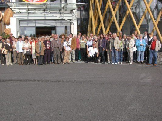 Eine Gruppe von Menschen, wahrscheinlich Touristen, steht in einer Reihe vor einem Gebäude mit einer Holzstruktur.