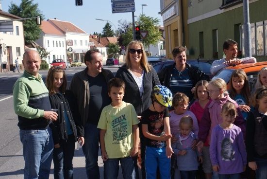 Eine Gruppe von Erwachsenen und Kindern posiert für ein Foto auf einer Straße, mit Gebäuden und Verkehrszeichen im Hintergrund.