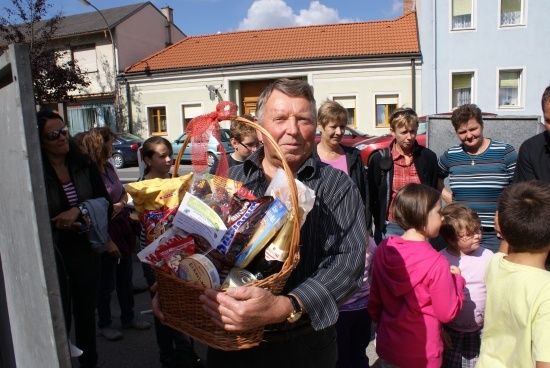 Ein Mann hält einen Korb mit Essen und Snacks, umgeben von einer Gruppe von Menschen in einem Wohngebiet.