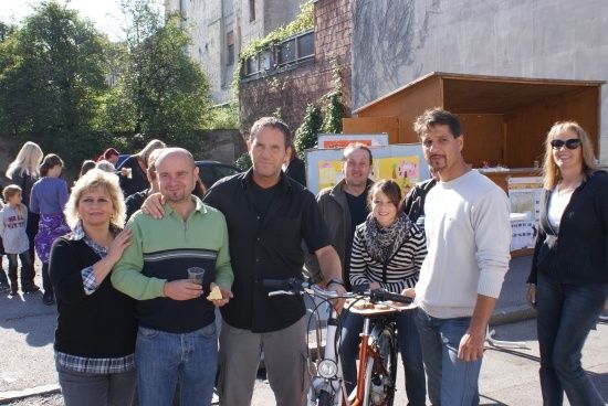 Eine Gruppe von Menschen, die auf einer Straße stehen, einige mit Fahrrädern, lächeln für ein Foto.
