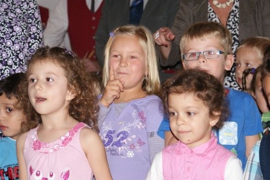 Eine Gruppe von Kindern, einschließlich Mädchen und Jungen, steht in einem Raum, möglicherweise bei einer Schulveranstaltung.