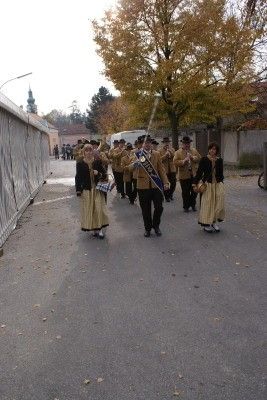 Eine Blaskapelle in traditionellen Kostümen zieht eine Straße entlang, angeführt von einer Frau.