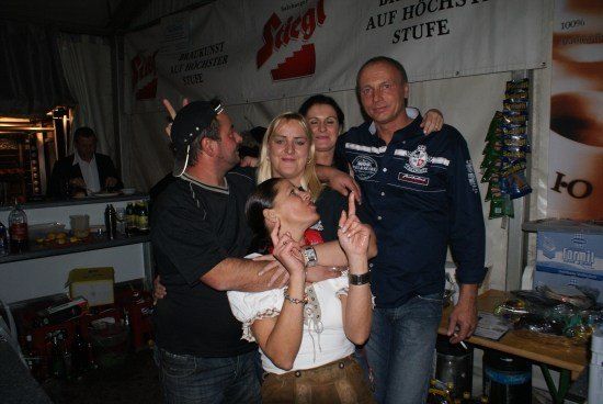 Eine Gruppe von Menschen posiert für ein Foto in einer Bar mit einem Banner im Hintergrund.