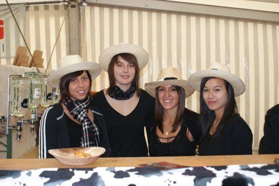 Vier Frauen in Cowboy-Hüten posieren für ein Foto vor einem Holztresen mit einer Schüssel Essen.