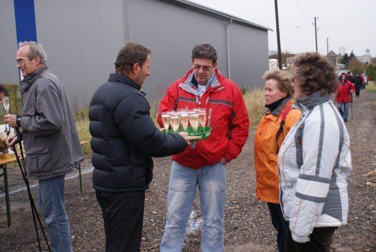 Eine Gruppe von Menschen in Winterkleidung steht draußen, ein Mann hält eine Schale mit Champagnergläsern.