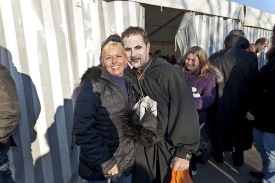 Eine Frau und ein Mann, der als Vampir verkleidet ist, posieren für ein Foto in einer Menschenmenge.
