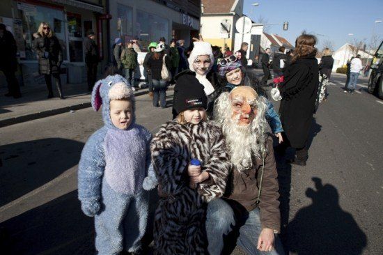 Eine Gruppe von Menschen in Kostümen auf einer Straße, mit einigen anderen, die im Hintergrund gehen.