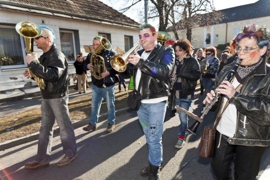 Eine Gruppe von Menschen in Punk-Kleidung spielt Blechblasinstrumente bei einer Straßenparade.