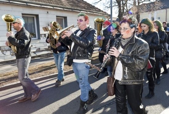 Eine Gruppe von Musikern in Punk-Kleidung zieht spielend mit Blech- und Holzblasinstrumenten die Straße entlang.