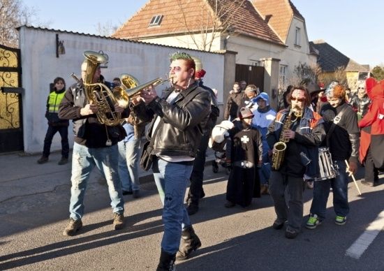 Eine Gruppe von Musikern in Kostümen spielt Blechblasinstrumente auf einer Straße mit Zuschauern.