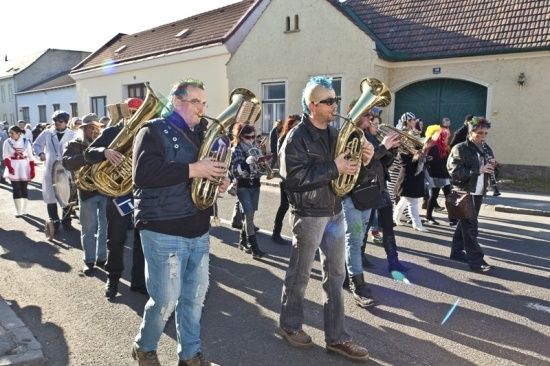 Eine Gruppe von Musikern, die Blechblasinstrumente spielen, geht vor Gebäuden eine Straße entlang.