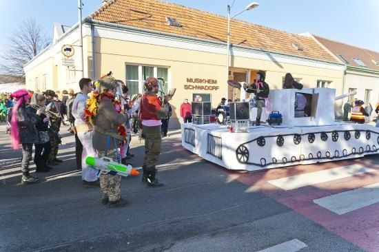 Eine Gruppe von Menschen in Kostümen tritt auf einem Panzer-förmigen Wagen in der Mitte der Straße auf.