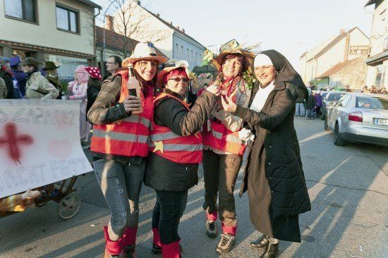 Vier Menschen in Kostümen, darunter eine Nonne, posieren für ein Foto auf einer Straße während eines Umzugs.