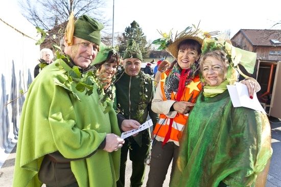Eine Gruppe von Menschen in grünen Kostümen und Hüten steht draußen, lächelt und posiert für ein Foto.