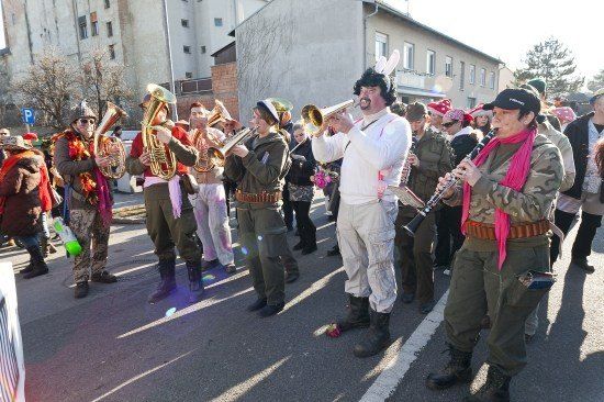 Eine Gruppe von Menschen in Militäruniformen und Mützen spielt Musikinstrumente auf der Straße.